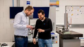 Zwei Mitarbeiter der Firma Ros begutachten ein technisches Bauteil