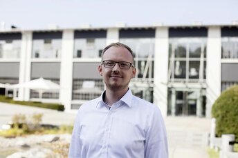 Mitarbeiter der Firma Brose steht vor dem Firmengebäude