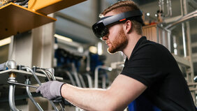 Junger Mann mit Schutzbrille und Handschuhen arbeitet an einer Maschine