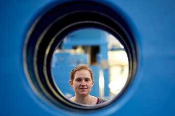 Mitarbeiterin der Firma Lasco schaut durch ein Rohr