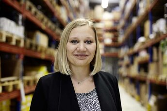 Mitarbeiterin der Firma LEISE steht zwischen Lagerregalen