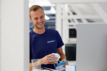 lächelnder Mitarbeiter der Baechlein GmbH vor Computer