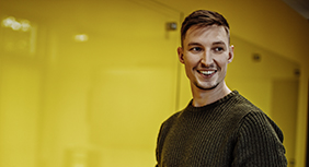 Lächelnder junger Mann vor gelber Wand