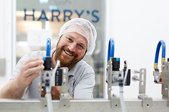 Lächelnder Mitarbeiter der Firma Harrys bedient eine Maschine