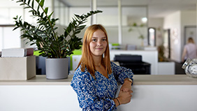 Junge Mitarbeiterin der Firma Max Carl neben Grünpflanze