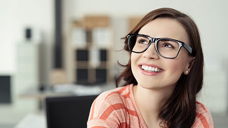 Lächelnde dunkelhaarige Frau mit modische schwarzer Brille