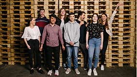 Azubis der Firma Prodinger stehen vor einem Palettenstapel